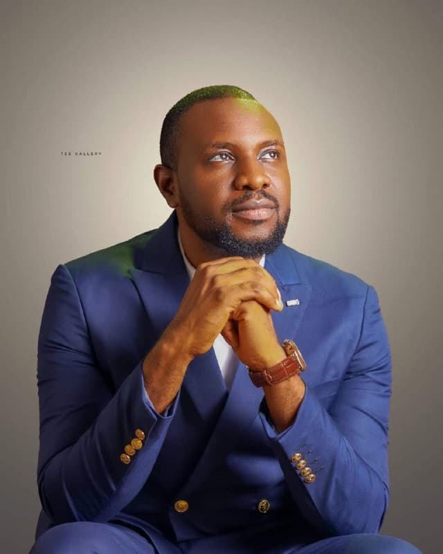 Reverend Benjamin A. Maji in a blue suit, hands clasped in thought